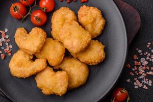 Delicious fresh crispy chicken nuggets on a dark concrete background photo