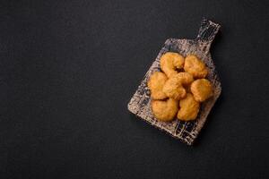 Delicious fresh crispy chicken nuggets on a dark concrete background photo