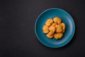 Delicious fresh crispy chicken nuggets on a dark concrete background photo