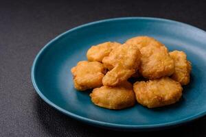 Delicious fresh crispy chicken nuggets on a dark concrete background photo