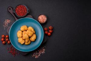Delicious fresh crispy chicken nuggets on a dark concrete background photo