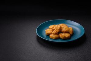 Delicious fresh crispy chicken nuggets on a dark concrete background photo