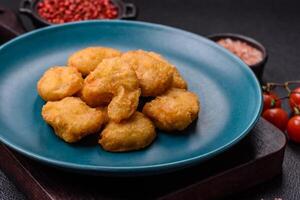 Delicious fresh crispy chicken nuggets on a dark concrete background photo