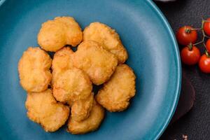 Delicious fresh crispy chicken nuggets on a dark concrete background photo