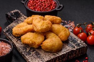 Delicious fresh crispy chicken nuggets on a dark concrete background photo