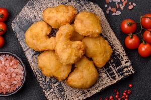 Delicious fresh crispy chicken nuggets on a dark concrete background photo