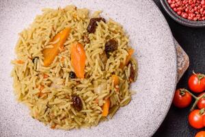 Delicious fresh pilaf with rice, carrots, meat, onions, spices and berries photo