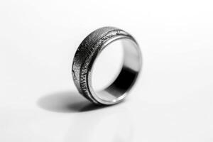 A silver ring with a black band on a white surface photo