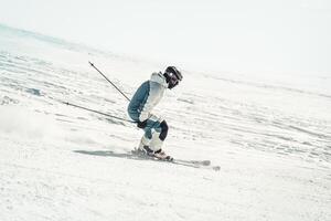 Close up dynamic sports banner of man skier on piste ski downhill fast motion in Alps. Active winter holidays, skiing downhill in overcast day. Ski rides on the track with swirls of fresh snow photo
