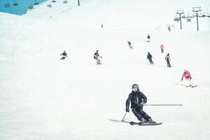 Close up dynamic sports banner of many skiers on piste ski downhill fast motion in caucasus. Active winter holidays, skiing downhill in overcast day. Ski rides on the track with swirls of fresh snow photo