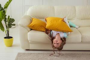 Child with a cast on a broken wrist or arm smiling and having fun on a couch. Positive attitude, recovery and kid concept. photo