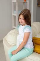 Child with a cast on a broken wrist or arm smiling and having fun on a couch. Positive attitude, recovery and kid concept. photo