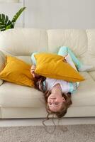 Child with a cast on a broken wrist or arm smiling and having fun on a couch. Positive attitude, recovery and kid concept. photo