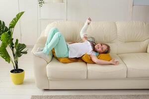 Child with a cast on a broken wrist or arm smiling and having fun on a couch. Positive attitude, recovery and kid concept. photo