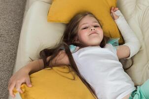Child with a cast on a broken wrist or arm smiling and having fun on a couch. Positive attitude, recovery and kid concept. photo