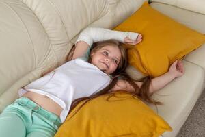 Child with a cast on a broken wrist or arm smiling and having fun on a couch. Positive attitude, recovery and kid concept. photo