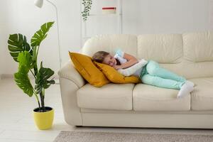 Child with a cast on a broken wrist or arm lying on a couch. Recovery and kid concept. photo