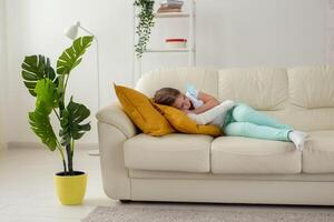 Child with a cast on a broken wrist or arm lying on a couch. Recovery and disease concept. photo