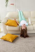 Child with a cast on a broken wrist or arm smiling and having fun on a couch. Positive attitude, recovery and kid concept. photo