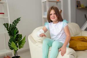 Child with a cast on a broken wrist or arm smiling and having fun on a couch. Positive attitude, recovery and kid concept. photo