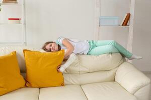 Child with a cast on a broken wrist or arm smiling and having fun on a couch. Positive attitude, recovery and kid concept. photo