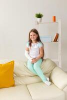 Child with a cast on a broken wrist or arm smiling and having fun on a couch. Positive attitude, recovery and kid concept. photo