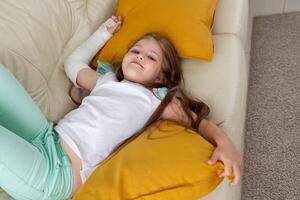 Child with a cast on a broken wrist or arm smiling and having fun on a couch. Positive attitude, recovery and kid concept. photo