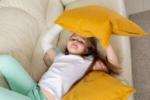 Child with a cast on a broken wrist or arm smiling and having fun on a couch. Positive attitude, recovery and kid concept. photo