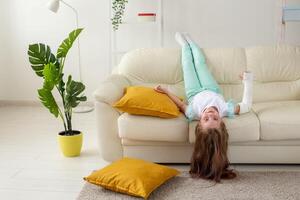 Child with a cast on a broken wrist or arm smiling and having fun on a couch. Positive attitude, recovery and kid concept. photo