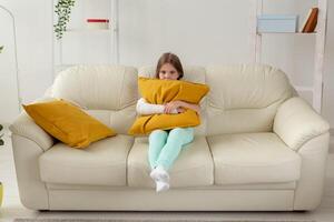 Child with a cast on a broken wrist or arm sitting on a couch. Recovery and disease concept. photo