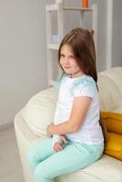 Child with a cast on a broken wrist or arm smiling and having fun on a couch. Positive attitude, recovery and kid concept. photo