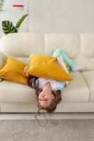 Child with a cast on a broken wrist or arm smiling and having fun on a couch. Positive attitude, recovery and kid concept. photo