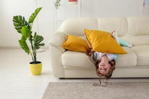 Child with a cast on a broken wrist or arm smiling and having fun on a couch. Positive attitude, recovery and kid concept. photo