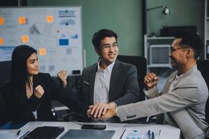 Group of colleagues engaging in a discussion during a business meeting in a conference room. Happy business people, men and women, collaborating and working towards their shared goals. photo