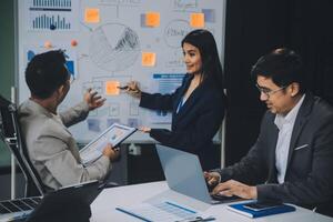 Group of confident business people point to graphs and charts to analyze market data, balance sheet, account, net profit to plan new sales strategies to increase production capacity. photo