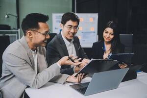 Group of colleagues engaging in a discussion during a business meeting in a conference room. Happy business people, men and women, collaborating and working towards their shared goals. photo