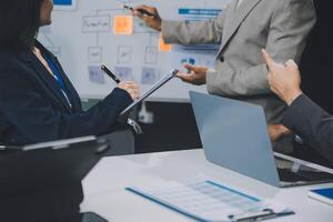 Group of confident business people point to graphs and charts to analyze market data, balance sheet, account, net profit to plan new sales strategies to increase production capacity. photo