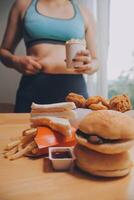 To eat or not. Cheerless plump woman looking at the burger while thinking to eat it or not photo