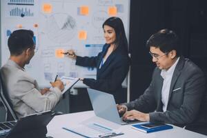 Group of confident business people point to graphs and charts to analyze market data, balance sheet, account, net profit to plan new sales strategies to increase production capacity. photo