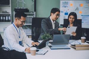Group of colleagues engaging in a discussion during a business meeting in a conference room. Happy business people, men and women, collaborating and working towards their shared goals. photo