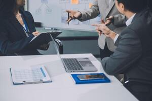 Group of confident business people point to graphs and charts to analyze market data, balance sheet, account, net profit to plan new sales strategies to increase production capacity. photo