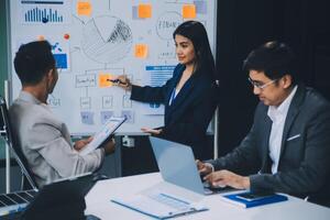 Group of confident business people point to graphs and charts to analyze market data, balance sheet, account, net profit to plan new sales strategies to increase production capacity. photo