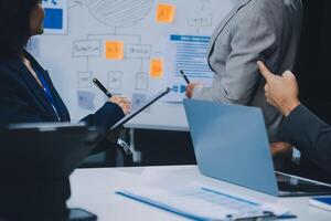 Group of confident business people point to graphs and charts to analyze market data, balance sheet, account, net profit to plan new sales strategies to increase production capacity. photo
