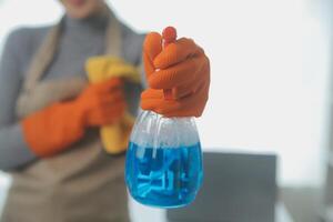 Woman cleaning table using rag and diffuser at home. photo