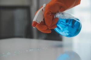 Woman cleaning table using rag and diffuser at home. photo