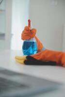 Woman cleaning table using rag and diffuser at home. photo