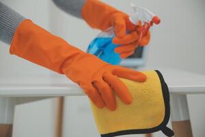 Woman cleaning table using rag and diffuser at home. photo