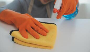 Woman cleaning table using rag and diffuser at home. photo