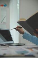 Charming Young asian businesswoman sitting on laptop computer in the office, making report calculating balance Internal Revenue Service checking document. photo