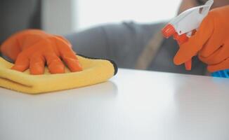 Woman cleaning table using rag and diffuser at home. photo